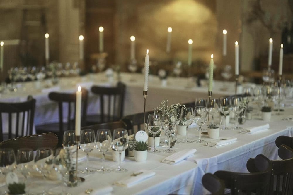 Longue table dressée aux chandelles, nappes blanches et verres à pied