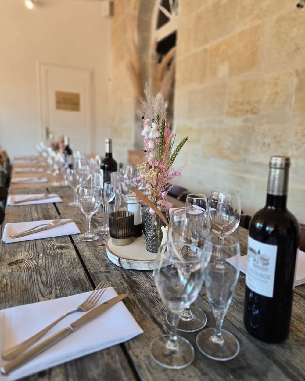 Table en bois dressée, verres, bouteille de vin et bouquet séché