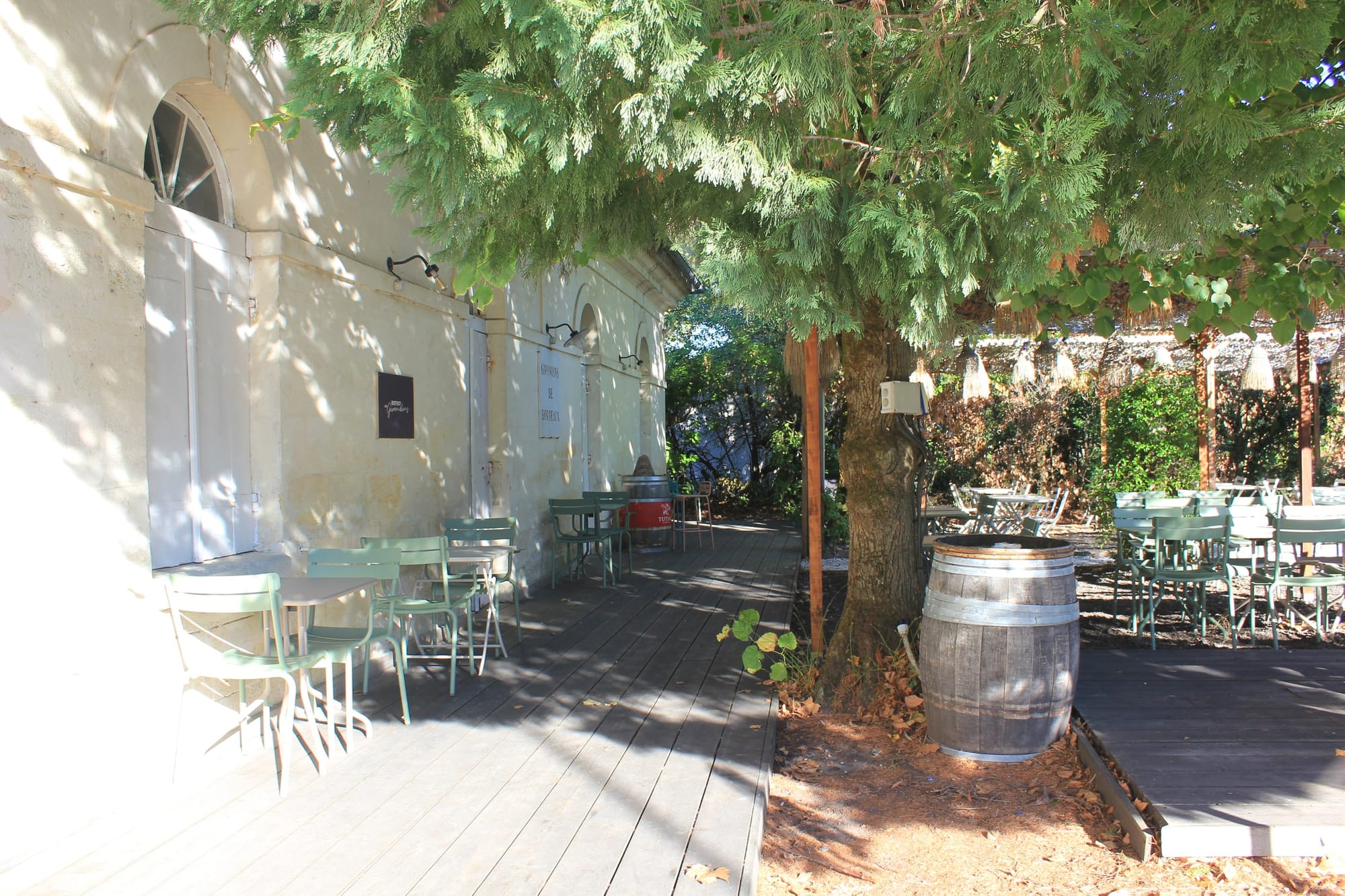 Terrasse du Bistrot à l'ombre des arbres, tables et chaises de jardin