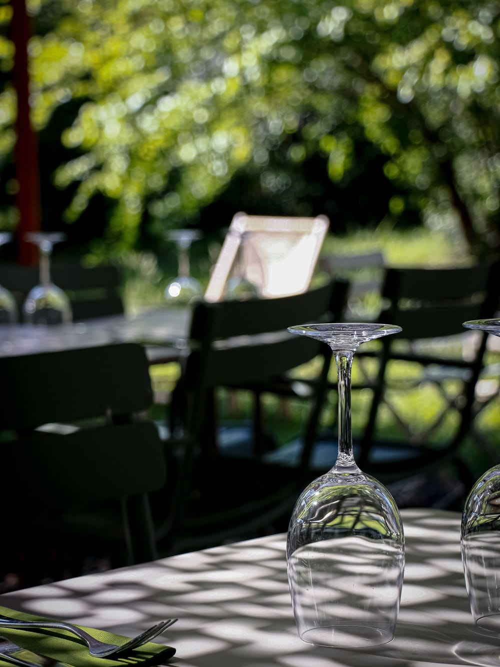 Table de terrasse à l'ombre des arbres, verres retournés