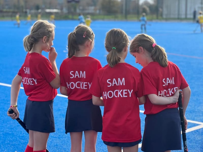 Jeunes joueuses du SAM Hockey en maillot rouge sur le terrain bleu